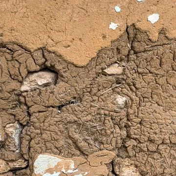 Adobe wall with stone and straw. Brown textured background. Stock Photos