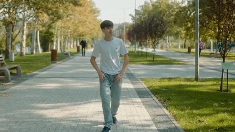 Adolescent Life in Motion Walking Through a Sunny Park Stock Footage 287192879