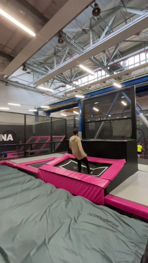 Adolescent skillfully performs back flip onto padded indoor surface Stock Footage 335358639