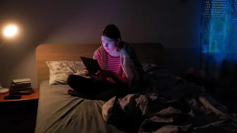 Adolescent struggling with insomnia using tablet under room light Vídeo Stock 336669272