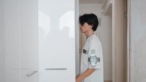 An adolescent systematically arranges storage units within small chamber. Young Video stock 337455941