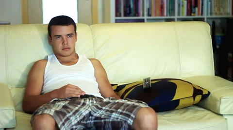 Adolescent, young boy, sitting on the sofa alone, television and mobile phones. Stock Footage 38418029