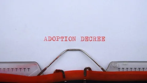 Adoption decree - phrase printed on an old typewriter in red letters, close up. Video stock 128400851