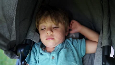 Adorable 2 year old child asleep inside stroller. One little kid napping an.. Video stock 242852973