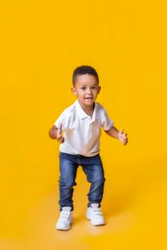 Adorable afro toddler boy showing thumb up gesture over yellow background Stock Photos