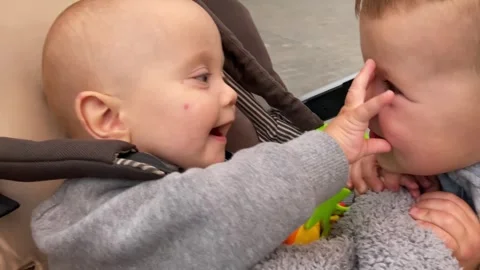 An Adorable and Cute Interaction Between Two Extremely Happy Babies Sitting in a Video stock 304731420