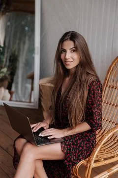 Adorable and happy long haired brunette woman working remotely in a bungalow Stock Photos