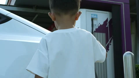 Adorable asian child boy using electric car charge with mom in ev station Stock Footage 253404211
