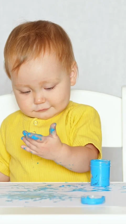 Adorable baby exploring creativity through finger painting with blue paint Stock-Footage 341284774