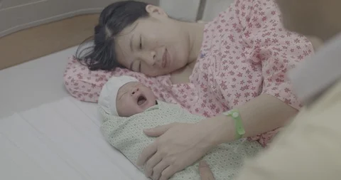 Adorable baby lying on bed surrounded with caring parents in the Maternity ho Stock Footage 127765547