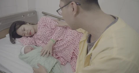 Adorable baby lying on bed surrounded with caring parents in the Maternity ho Stock Footage 127765852