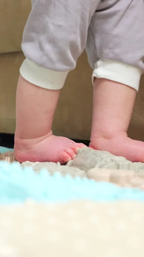 Adorable babys feet taking first steps on a colorful orthopedic massage mat, a Stock Footage 341285280