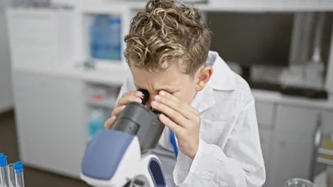 Adorable blond boy scientist, smiling confidently while working with a micr.. Stock Footage 261376566