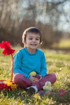 Adorable boy in the park, having fun with colored eggs for Easter Stock Photos