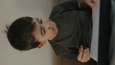 Adorable boy, sitting on the sofa, thoroughly immersed in literature sitting in Stock Footage 264022150