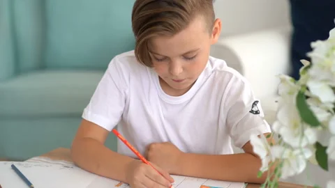 Adorable boy sitting at a table and concentrating on a piece of paper Stock Footage 115089942