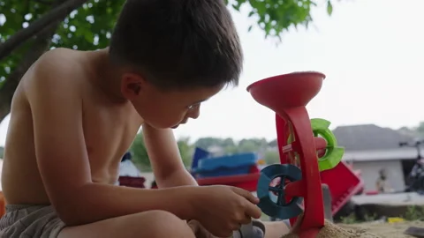 Adorable boy without clothes standing in the sand in the backyard playing with a Stock Footage 252534324