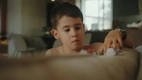 Adorable caucasian boy playing with car toys sitting on sofa at home. Education Stock Footage 252248731