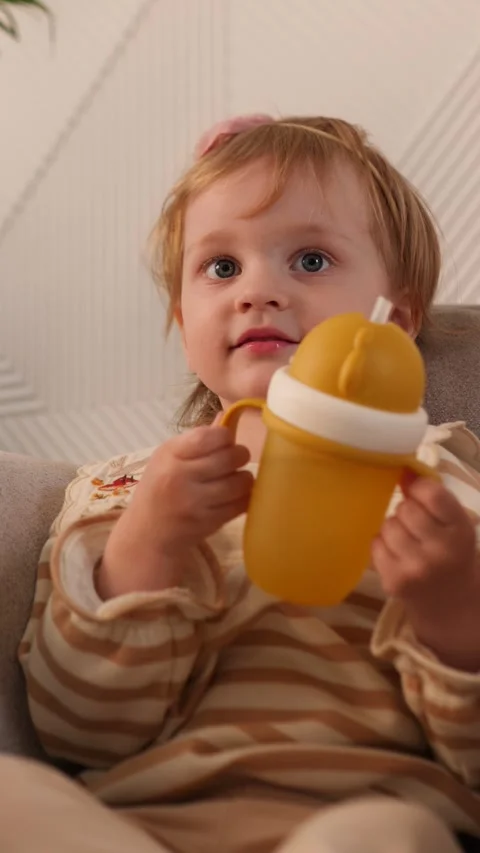 An Adorable Child Drinking from a Cup in a Cozy and Inviting Setting that Stock Footage 312056260