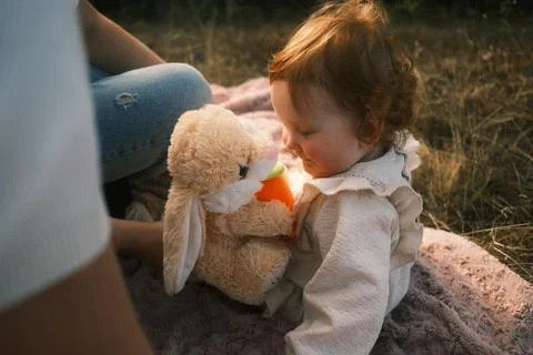 An adorable child is joyfully playing with a cuddly bunny toy amidst the nature Stock Photos