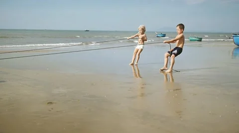 Adorable children pulling a rope with wheels for fishing boat on the beach. Stock-Footage 56479800