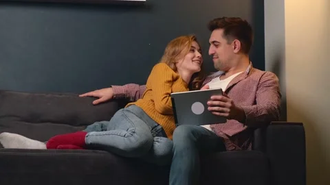 Adorable couple are lying on bed and smile while using a tablet and relaxing Stock Footage 147036348