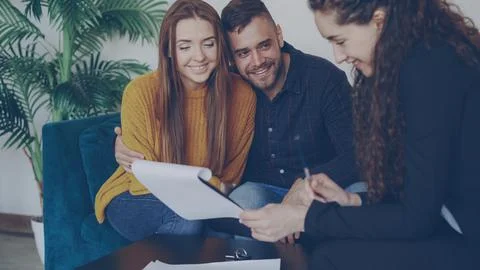 Adorable couple is checking papers during meeting with realtor in nice new Stock Photos