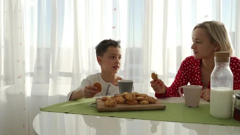 An adorable cute caucasian boy is eating cookie beside his young mother with Video stock 103673495