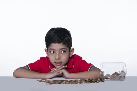 Adorable cute child thinking while counting coins in a glass jar, white backg... Stock Photos