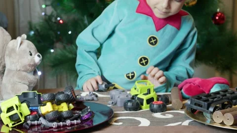 Adorable elf kid, in Santa Claus workshop fixing toys for kids with his friend Stock Footage 259392012
