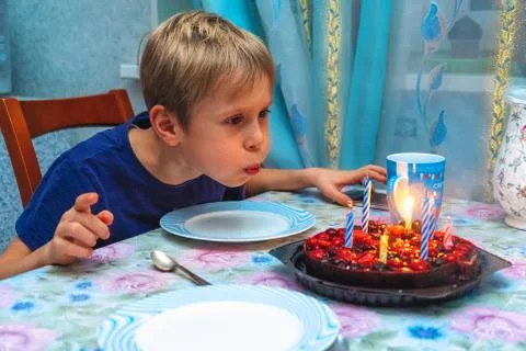 Adorable four year old kid celebrating his birthday and blowing candles on Stock Photos