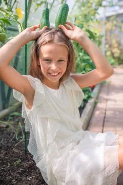 Adorable girl having fun in greenhouse. Portrait of kid with basket with Stock Photos