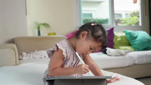 Adorable girl using tablet on couch indoor. Home learning concept. Stockbeeldmateriaal 199432418