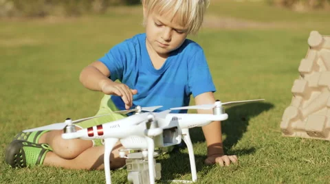 Adorable happy child assembling modern drone on the green grass lawn Stock-Footage 61449190