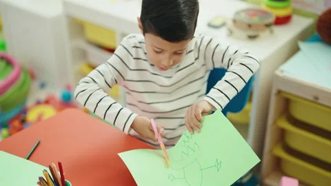 Adorable hispanic boy student cutting paper at kindergarten Stock Footage 230030499