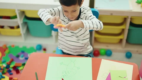 Adorable hispanic boy student smiling confident cutting paper at kindergarten Video stock 231509709