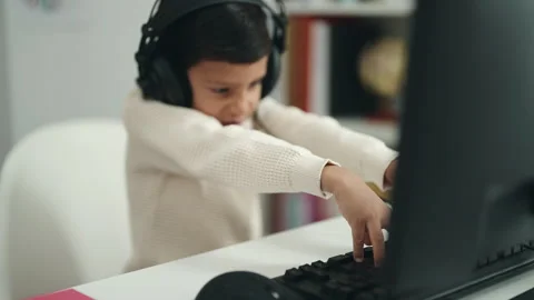 Adorable hispanic boy student using computer sitting on table at classroom Video stock 229564751