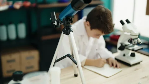 Adorable hispanic boy student using telescope writing on notebook at labora.. Stock Footage 230922246