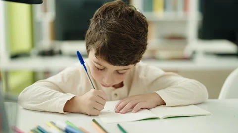 Adorable hispanic boy student writing on notebook at classroom Stock Footage 230024591