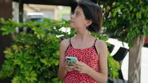 Adorable hispanic girl using smartphone with serious expression at street Stock Footage 206669960