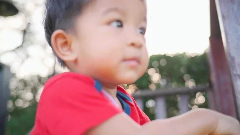 Adorable infant 1-2 year boy playing in tree park playgound sunset light boy Stock Footage 124338777