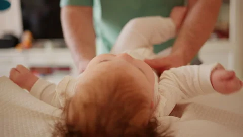 Adorable infant lying on a padded surface during supervised tummy time exercise Stock Footage 336928363