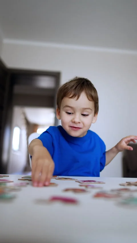 Adorable joyful kid claps hands looking at desk with puzzles. Stock Footage 297008573