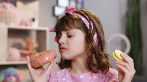 Adorable kid girl biting piece of donut ... | Stock Video | Pond5