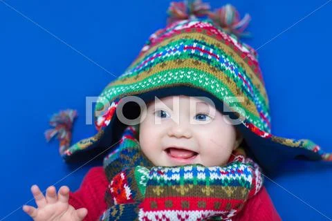 Adorable little baby girl in a big knitted hat and colorful scarf Stock Photos