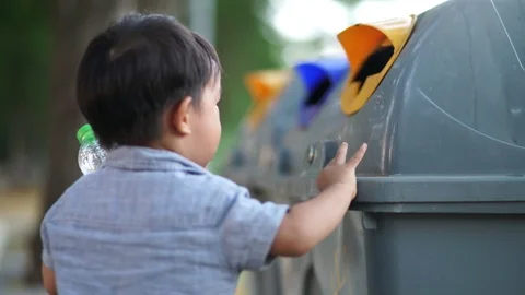 Adorable little boy keep clean plastic water bottle into trash bin in park Stock Footage 126083767