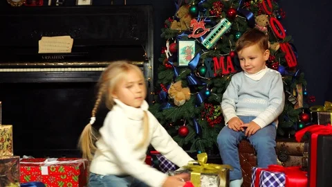 Adorable little brother refusing to take beautiful wrapped Christmas present Stock Footage 99405169