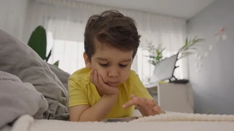 Adorable little child lying on sofa touching mobile phone screen Stock Footage 245594496