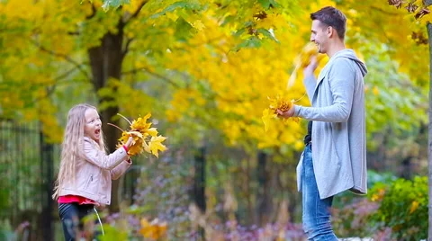 Adorable little girl and happy father enjoy fall day in autumn park outdoors Stock Footage