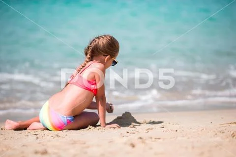 Adorable little girl drawing on sand at beach during summer vacation Stock Photos
